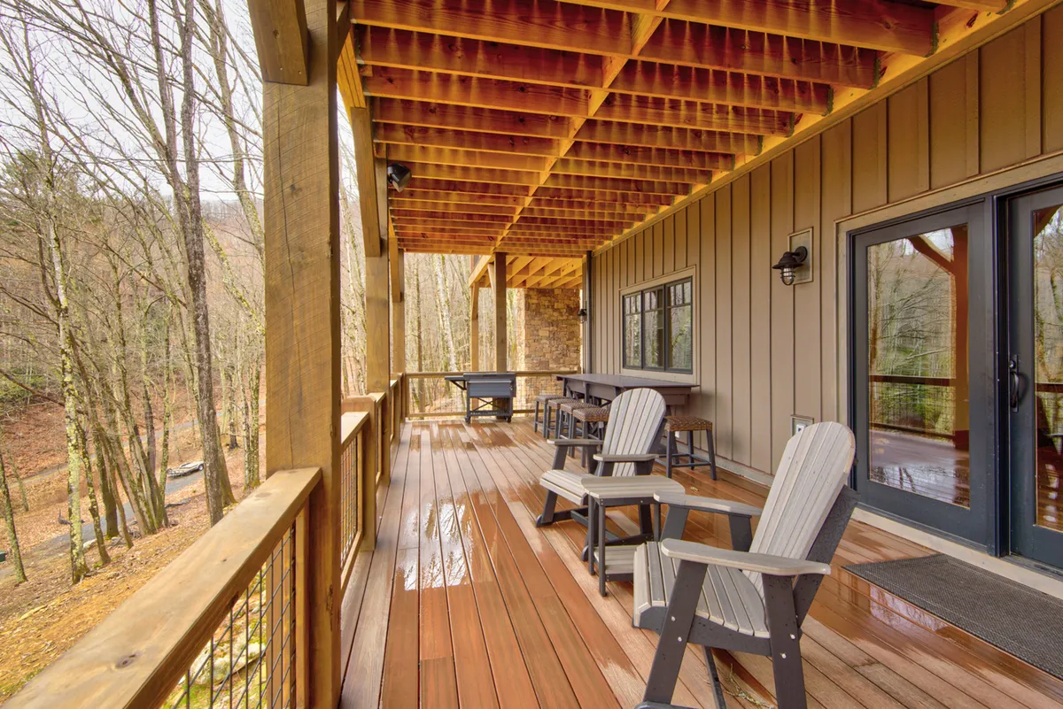 A serene deck scene surrounded by trees, furnished with rocking chairs and a table, evoking moments of tranquil relaxation. The setting is ideal for morning coffee, reading, or gathering with friends while enjoying the changing seasons and abundant wildlife.