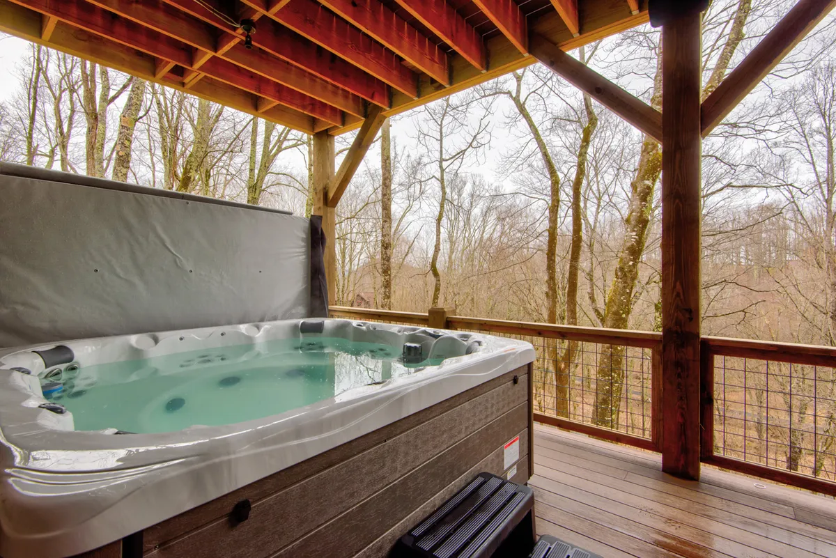 A private hot tub sits on a wooden deck, nestled among tall trees, offering a tranquil retreat for relaxation and informal team bonding. The setting emphasizes privacy and immersion in nature, ideal for unwinding after meetings or group activities.